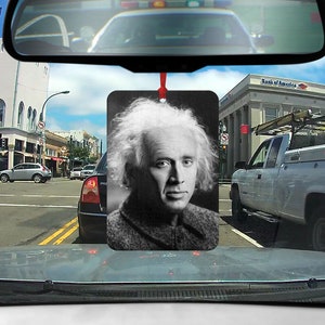 Könnte beinhalten: Schwarzweißfoto eines Mannes mit weißem Haar und Bart. Er trägt einen dunklen Pullover und blickt in die Kamera. Das Foto ist auf einem Auto-Lufterfrischer gedruckt.