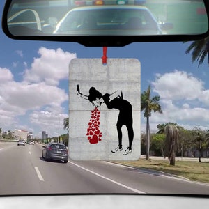 Könnte beinhalten: Ein Auto-Lufterfrischer mit einem Schwarzweißbild einer Person, die Herzen auf einen grauen Hintergrund erbricht.