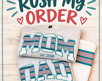 May include: Two heather gray sweatshirts featuring embroidered lettering in teal and red striped patterns. One sweatshirt displays the word MOM and the other DAD, both with the text est. 2026. A folded white towel with matching striped trim is included.