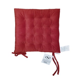 May include: Red velvet chair cushion with a tufted design and ties. The cushion has a tag that says "My Store" and "Infinity".