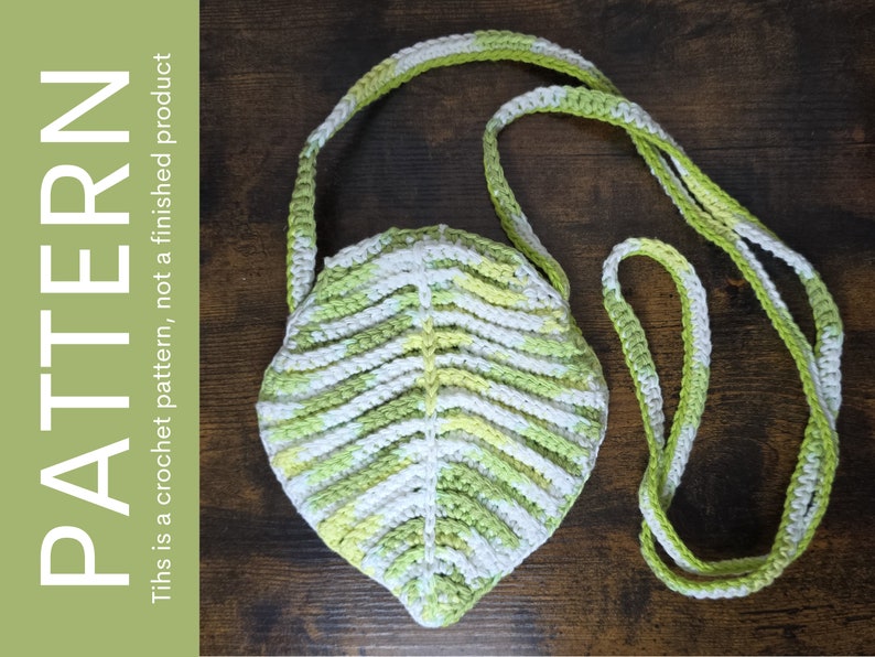 May include: A crocheted leaf-shaped bag with a green, white, and yellow color scheme. The bag has a long strap for carrying over the shoulder.