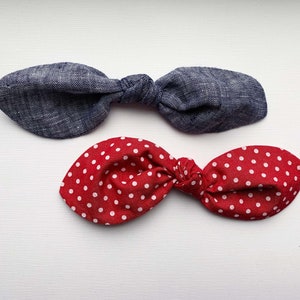 May include: Two fabric hair bows, one blue denim and one red with white polka dots.