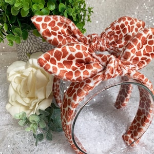 Peut inclure: Un serre-t&ecirc;te marron et blanc &agrave; motif avec un n&oelig;ud. Le serre-t&ecirc;te est fait d'un tissu doux et pelucheux et est parfait pour ajouter une touche de fantaisie &agrave; n'importe quelle tenue.