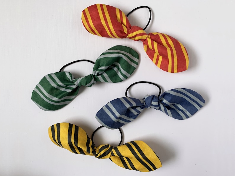 May include: Four striped fabric hair ties in red and yellow, green and white, blue and white, and yellow and black.