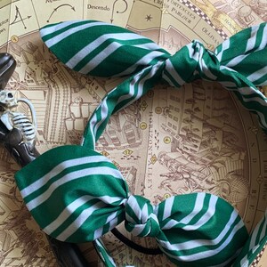 May include: A green and white striped headband with a bow. The headband is on a map with the words "Horizontalley", "Fair Fortune", and "The Fountain of", and "RE" visible.