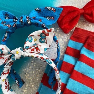 May include: Two red and blue striped headbands with a bow tie and a pair of red and blue striped socks. The headbands feature a pattern of the Cat in the Hat characters.