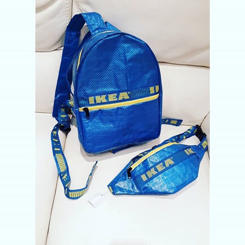 K&ouml;nnte beinhalten: Ein blaues und gelbes IKEA-Rucksack- und Bauchtaschen-Set. Der Rucksack hat eine Rei&szlig;verschlusstasche und verstellbare Tr&auml;ger. Die Bauchtasche hat einen Rei&szlig;verschluss und einen Gurt, der um die Taille oder die Schulter getragen werden kann.