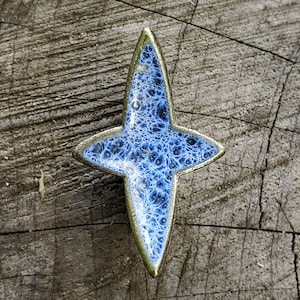 May include: A blue and gold ceramic star with a detailed pattern. The star is a decorative object.
