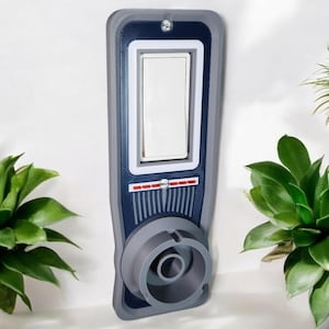 May include: A custom-designed light switch cover in shades of gray, navy blue, and white. The cover features a rectangular switch opening, a circular lower section, and a series of vertical lines. The design has a retro-futuristic aesthetic.