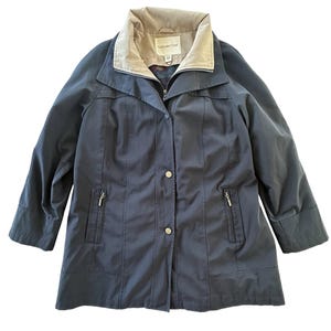 May include: A navy blue women's jacket with a tan collar and a zip-up front. The jacket has two zippered pockets and button closures. The brand name "Coldwater Creek" is visible on the collar.