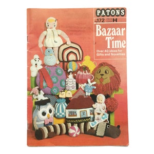 Puede incluir: Un libro de patrones de ganchillo vintage titulado "Bazaar Time" de Patons. La portada presenta una colorida variedad de juguetes de ganchillo, incluyendo un león, una muñeca, una casa, un búho y un arcoíris.
