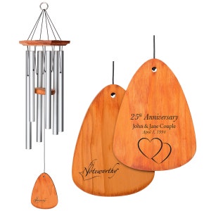 May include: A wooden wind chime with a personalized inscription that reads "25th Anniversary John & Jane Couple April 1, 1994". The inscription is accompanied by two intertwined hearts. The wind chime is made of natural wood and has a rustic look.