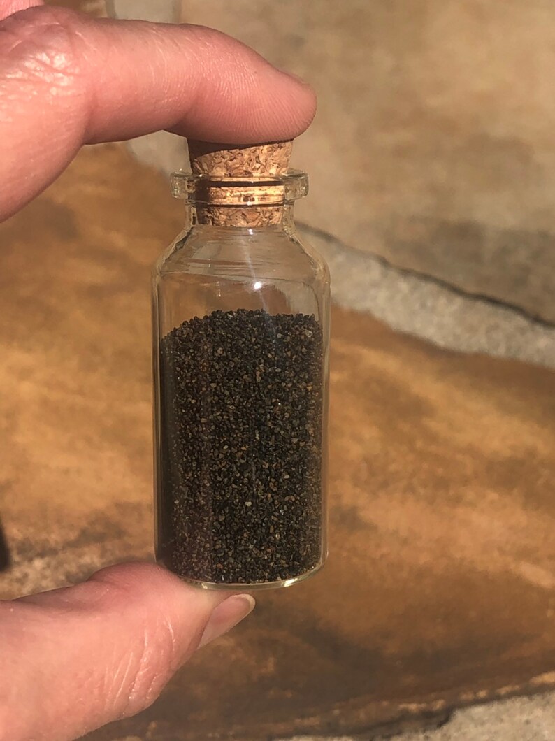 Puede incluir: Una peque&ntilde;a botella de vidrio con un tap&oacute;n de corcho llena de semillas negras.