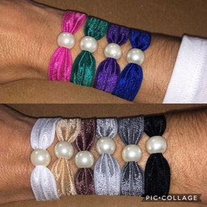 May include: A set of ten hair ties with pearl accents. The hair ties are made of a soft, stretchy material and come in a variety of colors, including pink, green, purple, blue, white, beige, brown, silver, gray, and black.