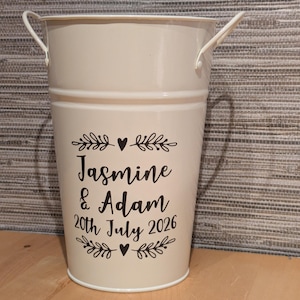 May include: A white ceramic mug with a black handle and the text "But First, Coffee" in a black, bold font. The mug is on a white surface.