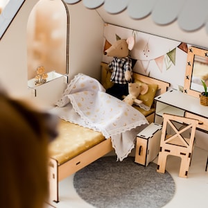 A miniature dollhouse with a bed, chairs, and other furniture, including a small mouse and a cat.