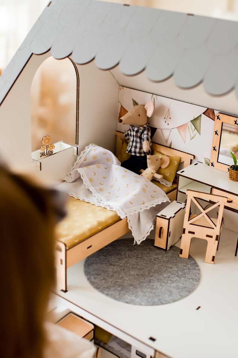 A miniature dollhouse with a bed, chairs, and other furniture, including a small mouse and a cat.