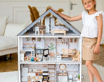 May include: A multi-story wooden dollhouse featuring a gray gabled roof and an open-front design. The interior includes detailed rooms with miniature furniture, including a kitchen, bedroom, and living area, decorated with printed wall art and patterns.