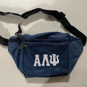 May include: A blue fanny pack with a white "ΑΔΨ" logo. The fanny pack has a black adjustable strap and two zippered compartments.