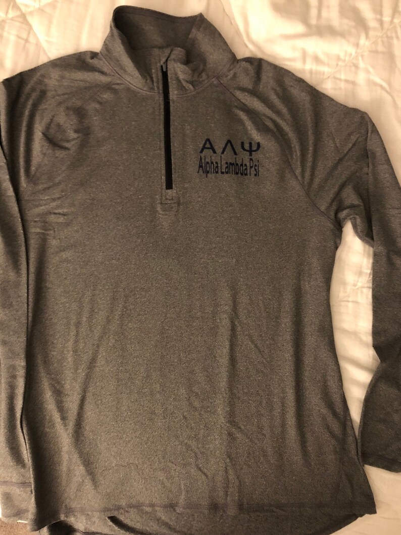 May include: A grey long-sleeved shirt with a zipped neck and the text "&Alpha;&Delta;&Psi; Alpha Lambda Psi" embroidered on the front.