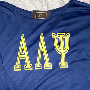 May include: A navy blue long-sleeved shirt with the Greek letters "ΑΑΨ" in yellow.