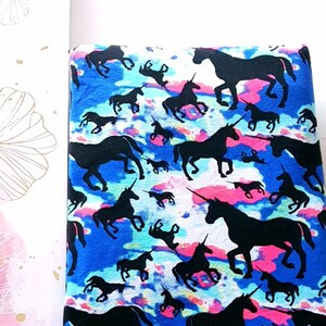 Puede incluir: Una tela azul con un patr&oacute;n de tie-dye blanco y rosa con siluetas de unicornios negros.