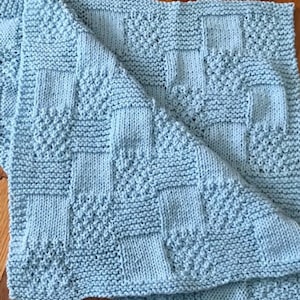 May include: A light blue knitted baby blanket with a diamond pattern.