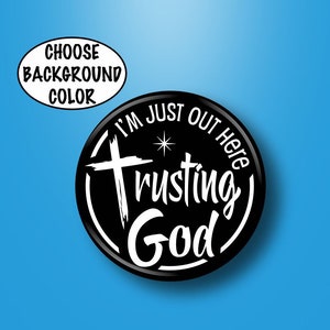 May include: Black and white button with the text "I'm Just Out Here Trusting God" with a cross and a star.