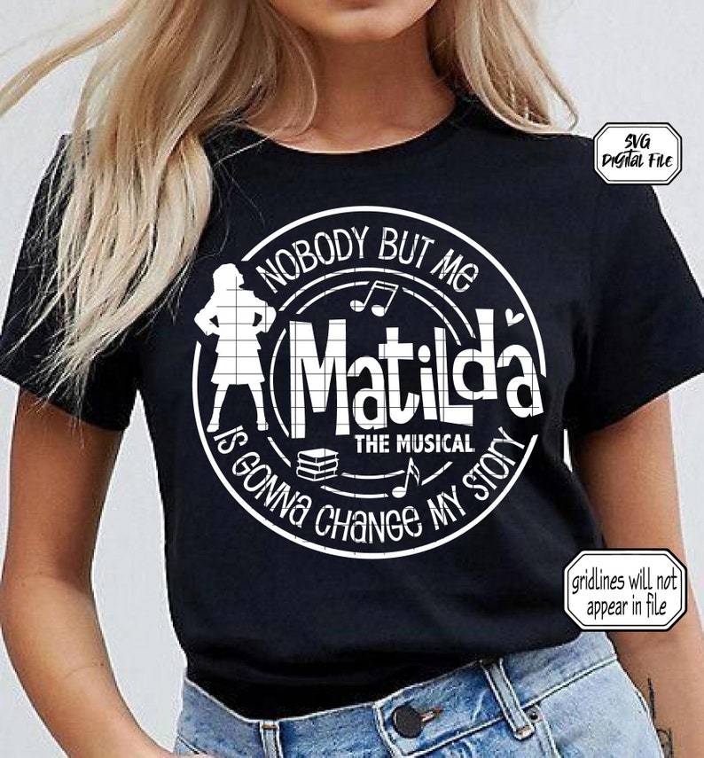 May include: Black t-shirt with a white circle design featuring the text "Nobody But Me Matilda The Musical Is Gonna Change My Story" and a silhouette of a girl holding books.
