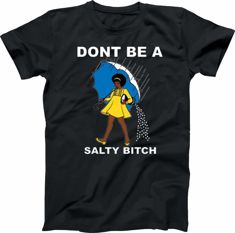 May include: Black t-shirt with the text "DONT BE A SALTY BITCH". The graphic features a woman in a yellow dress holding a blue umbrella, with salt pouring out of it. The design is a humorous statement.