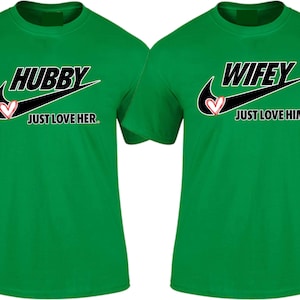 May include: Two green t-shirts with a black Nike swoosh and a red heart. The left shirt says "Hubby Just Love Her." The right shirt says "Wifey Just Love Him."