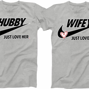 May include: Two grey t-shirts with a black Nike swoosh and a red heart. The left shirt says "Hubby Just Love Her." The right shirt says "Wifey Just Love Him."