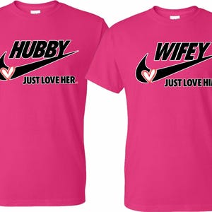 May include: Two pink t-shirts with a black Nike swoosh and the words "Hubby Just Love Her" and "Wifey Just Love Him" printed on them.