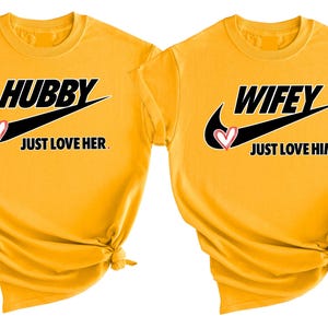 May include: Two yellow t-shirts with a black Nike swoosh and the words "Hubby Just Love Her" and "Wifey Just Love Him" printed on them.