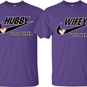 May include: Two purple t-shirts with a black Nike swoosh and the words "Hubby Just Love Her." and "Wifey Just Love Him." printed on them.
