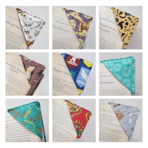 May include: Nine different Harry Potter themed fabric bookmarks. Each bookmark is a triangle shape with a different pattern and colour. The patterns include owls, Hogwarts houses, and other Harry Potter symbols. The bookmarks are all folded and placed on top of open books.