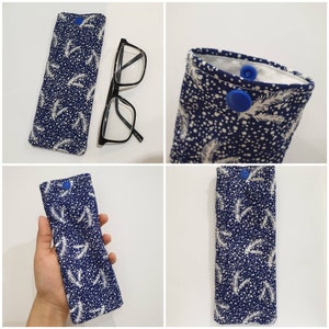 May include: A blue and white patterned glasses case with a blue button closure. The case is made of fabric and has a snowflake and leaf design.