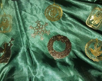 Pode incluir: Variedade de enfeites de Natal dourados sobre um fundo de tecido verde. Os enfeites incluem um floco de neve, uma coroa, um pássaro, um anjo e outras formas decorativas. Os enfeites estão pendurados em fios dourados.