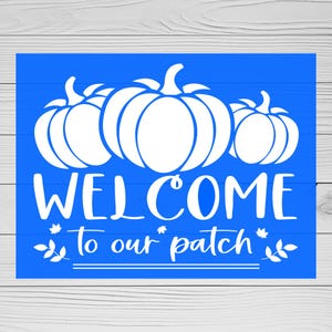 May include: A blue welcome sign with the text "Welcome to our patch" and three white pumpkins. The pumpkins are stylised and have a simple design.