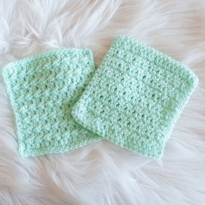 May include: Two crocheted squares in a light green color. The squares are made with a simple stitch pattern and have a soft, textured look.