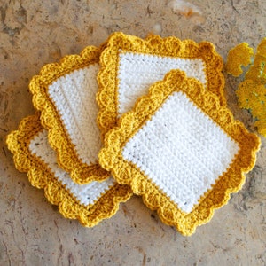 May include: Three crocheted dishcloths with a white center and a yellow crocheted border. The dishcloths are stacked on top of each other.