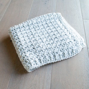 May include: A gray and white crocheted blanket with a textured pattern.