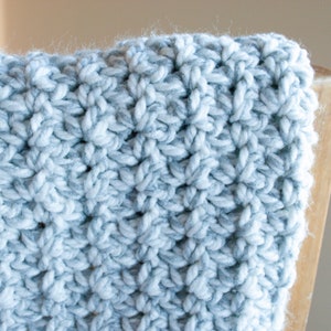 May include: Close-up of a crocheted blanket with a white and gray yarn pattern.