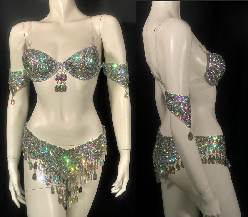 Pode incluir: Um conjunto de duas pe&ccedil;as composto por um suti&atilde; e uma parte de baixo a condizer, ambos ricamente decorados com strass iridescentes multicoloridos e cristais pendentes em forma de gota. O suti&atilde; tem al&ccedil;as transparentes e inclui bra&ccedil;adeiras a condizer.