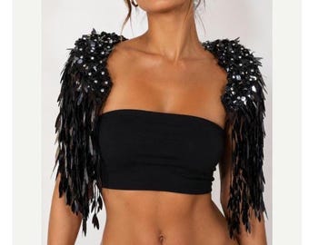 May include: A black strapless tube top paired with detachable shoulder bolero sleeves. The sleeves feature dense black sequin embellishments and long, dangling black fringe elements that extend down from the shoulders, creating a textured look.