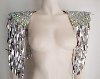 May include: A pair of silver sequined shoulder pieces with iridescent accents. Each piece features a fringe of silver sequins.