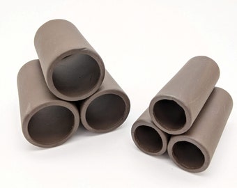 May include: Set of six brown ceramic aquarium tubes, arranged in two groups of three. The tubes are hollow and have a smooth, rounded finish.