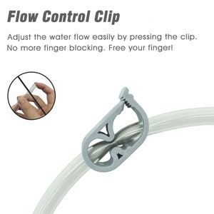 May include: A gray plastic flow control clip attached to a clear plastic tube. The clip has a lever that can be pressed to adjust the flow of water through the tube.