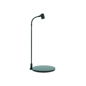 Pode incluir: Uma lâmpada de mesa preta ajustável com uma base redonda e um braço flexível. A lâmpada tem um abajur preto com uma textura estriada.