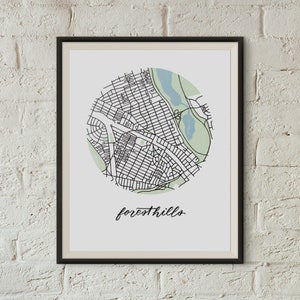May include: A black and white line art print of a map of Forest Hills, a neighborhood in Queens, New York City. The map is in a circle with the name of the neighborhood written in cursive below it.